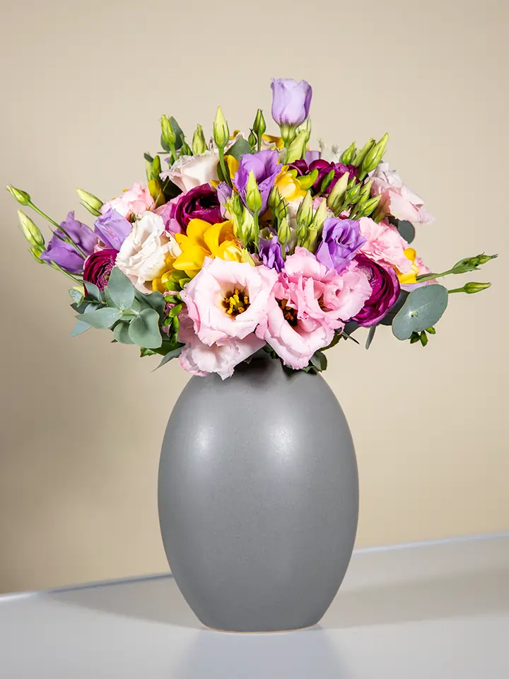 Bouquet lisianthus rosa e viola rose rosa fresie gialle in vaso grigio